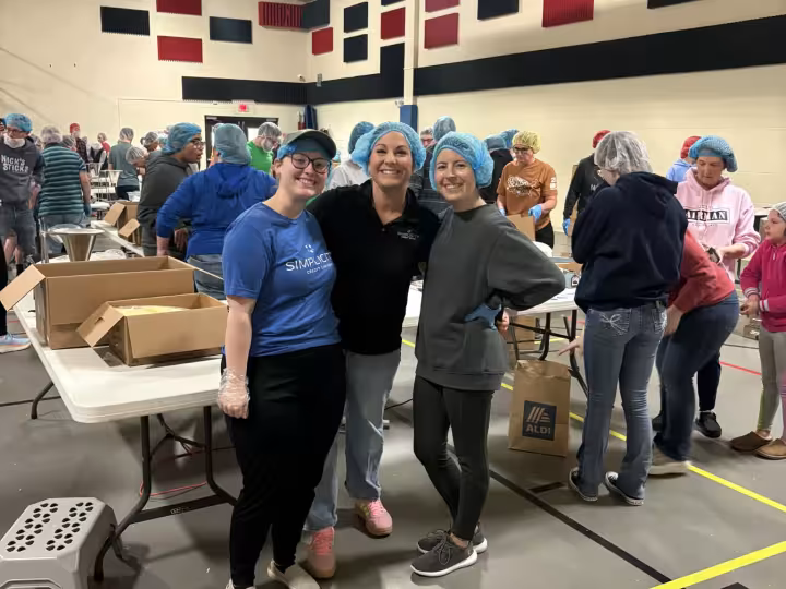 Simplicity staff in hairnets volunteering at a meal-packing event