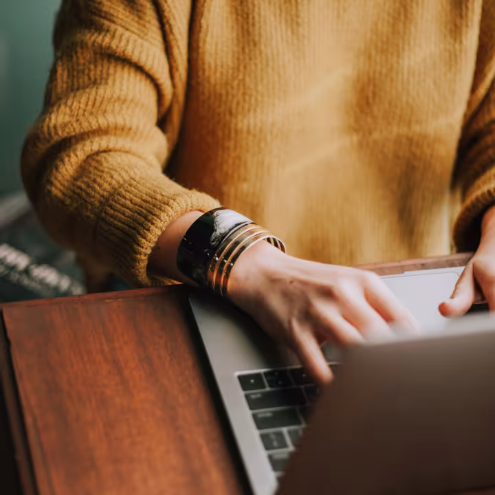 Hands typing on a laptop