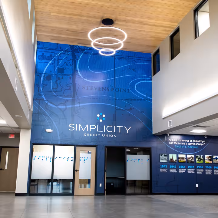 The two-story lobby of a Simplicity Credit Union branch, with a large blue Simplicity wall graphic